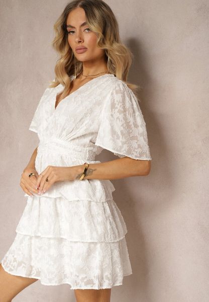 Biała Sukienka o Rozkloszowanym Kroju z Dekoltem w Serek i Falbankami Drapia. Białe sukienki damskie Renee, na imprezę, l, bez wzorów, eleganckie, bez kołnierzyka, bez ramiączek, mini, rozkloszowane. Za 149.99 zł.