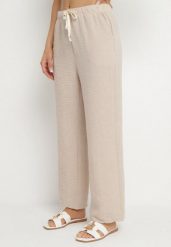 Beżowe Spodnie o Szerokim Kroju z Gumką i Wiązaniem w Talii Mirastra. Brązowe spodnie dresowe damskie Born2be, bez wzorów, z jeansu, eleganckie, trekkingowe. Za 39.99 zł.