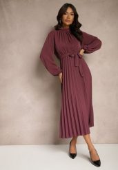Fioletowa Sukienka Plisowana o Rozkloszowanym Kroju ze Stójką Gumką i Paskiem Zinnoritta. Fioletowe sukienki damskie Renee, na co dzień, uniwersalny, bez wzorów, eleganckie, bez kołnierzyka, bez ramiączek, maxi, kopertowe. Za 89.99 zł.