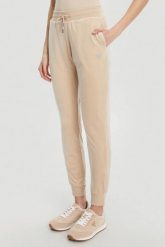 GUESS Beżowe damskie spodnie dresowe Couture, Rozmiar S. Brązowe spodnie dresowe damskie Guess, z aplikacjami, z dresówki. W wyprzedaży za 217.99 zł.