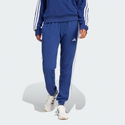 Spodnie Essentials 3-Stripes French Terry Cuffed. Białe spodnie dresowe damskie Adidas, bez wzorów, z materiału, sportowe. W wyprzedaży za 131.40 zł.