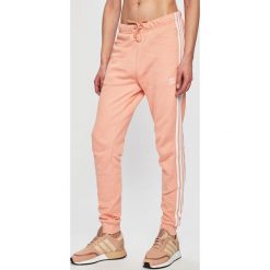 Adidas Originals - Spodnie sportowe. Czerwone spodnie dresowe damskie adidas Originals, bez wzorów, z bawełny, casualowe. W wyprzedaży za 199.90 zł.
