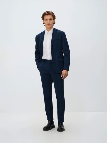 Garniturowe spodnie slim fit - granatowy. Niebieskie garnitury męskie Reserved, l, bez wzorów, z dzianiny. W wyprzedaży za 109.99 zł.