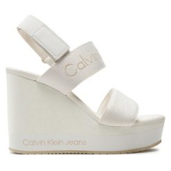 Sandały Calvin Klein Jeans. Białe sandały damskie Calvin Klein Jeans, bez wzorów, z jeansu, bez obcasa, na koturnie, bez zapięcia. Za 319.99 zł.