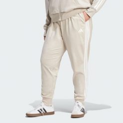 Spodnie Dresowe Essentials 3-Stripes (Dla Sylwetek Plus Size). Białe spodnie sportowe damskie Adidas, bez wzorów, z dresówki, sportowe, na fitness i siłownię. Za 219.00 zł.
