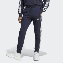 Spodnie dresowe męskie adidas Essentials French Terry Tapered Cuff 3-Stripes. Białe spodnie sportowe męskie Adidas, m, bez wzorów, z dresówki, do piłki nożnej. Za 182.00 zł.