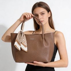 Torebka damska Rieker, ze skóry ekologicznej o prostej eleganckiej formie z ozdobną apaszką przy uchwycie wygodna do noszenia w dłoni i na ramieniu,. Brązowe shopperki damskie Rieker, bez wzorów, ze skóry ekologicznej, na ramię, bez dodatków. Za 279.00 zł.