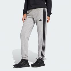 Spodnie Essentials 3-Stripes French Terry Cuffed. Czarne spodnie dresowe damskie Adidas, bez wzorów, z materiału, sportowe. Za 219.00 zł.