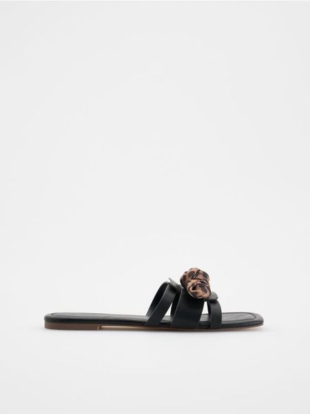 Klapki z ozdobnym wiązaniem - czarny. Czarne klapki damskie Reserved, bez wzorów, ze skóry, klasyczne, bez obcasa, bez zapięcia. W wyprzedaży za 32.99 zł.