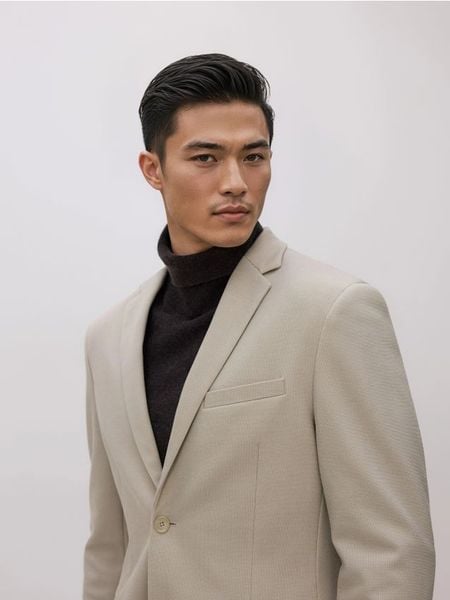 Marynarka slim fit - beżowy. Brązowe garnitury męskie Reserved, l, bez wzorów, z dzianiny, bez kołnierzyka, bez ramiączek. Za 259.99 zł.