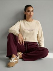 Bluza crewneck z haftowanym napisem NYC - kremowy. Białe bluzy damskie Sinsay, l, bez wzorów, bez ramiączek, bez kaptura. Za 39.99 zł.