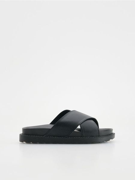 Klapki z imitacji skóry - czarny. Czarne klapki damskie Reserved, bez wzorów, ze skóry, bez obcasa, bez zapięcia. W wyprzedaży za 32.99 zł.