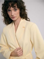 Marynarka z wiązaniem - jasnożółty. Żółte marynarki i żakiety damskie Reserved, bez wzorów, z tkaniny, bez kołnierzyka, bez ramiączek. Za 199.99 zł.