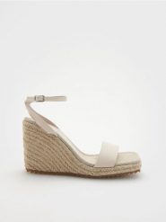Sandały na koturnie - złamana biel. Sandały damskie Reserved, bez wzorów, ze skóry, bez obcasa, na koturnie, bez zapięcia. W wyprzedaży za 45.99 zł.