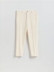 Garniturowe spodnie carrot - biały. Białe garnitury męskie Reserved, bez wzorów, z tkaniny. Za 169.99 zł.