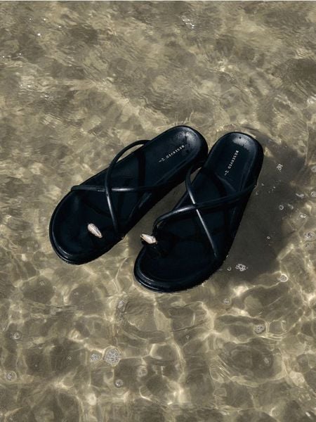 Klapki z ozdobnym detalem - czarny. Czarne klapki damskie Reserved, bez wzorów, ze skóry, bez obcasa, bez zapięcia. W wyprzedaży za 79.99 zł.