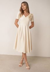Beżowa Elegancka Rozkloszowana Sukienka z Kwiatem 3D Eugorus. Brązowe sukienki damskie Born2be, na imprezę, l, z aplikacjami, eleganckie, bez kołnierzyka, bez ramiączek, midi, dopasowane. Za 249.99 zł.